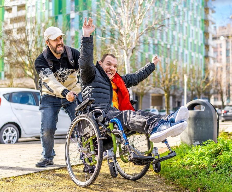 Young man with disability in a wheelchair spending the day with friend